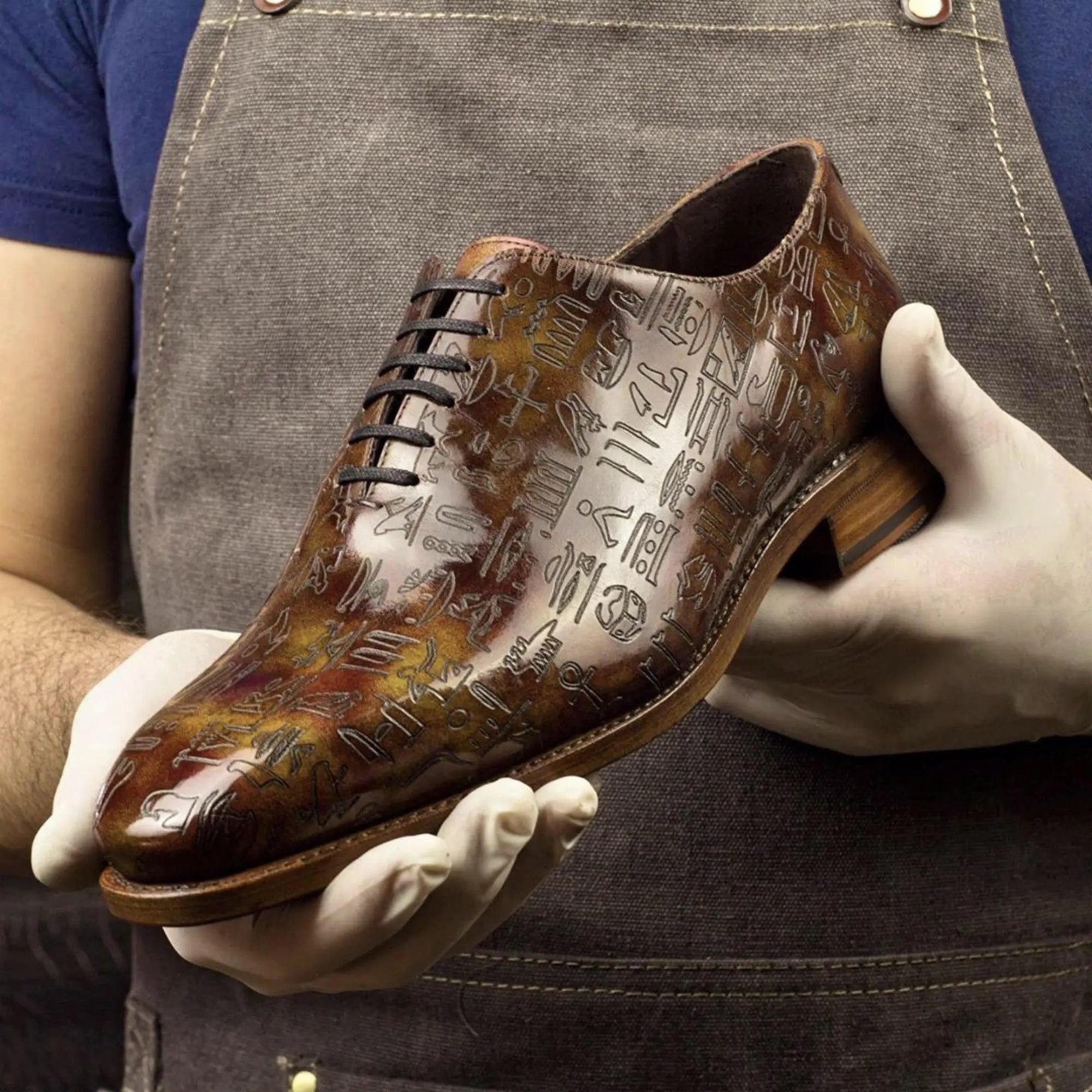 Brown leather dress shoe with hieroglyphic design.