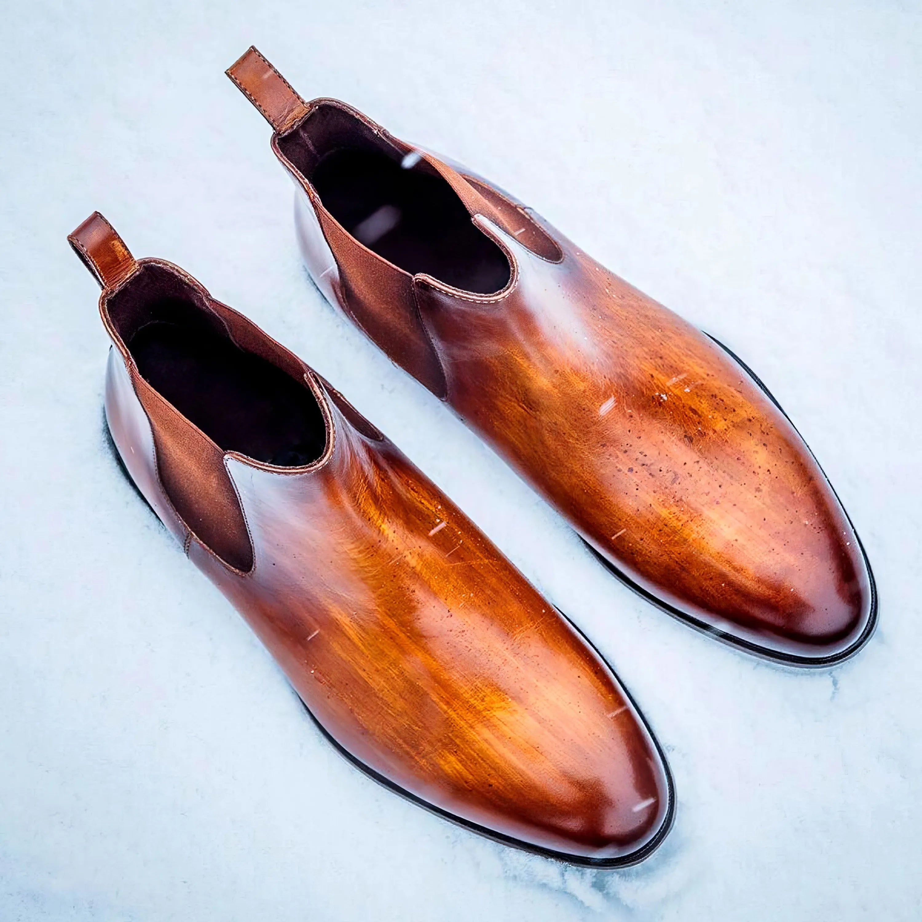 Polished brown leather chelsea boots with a sleek, pointed toe and elastic side panels.