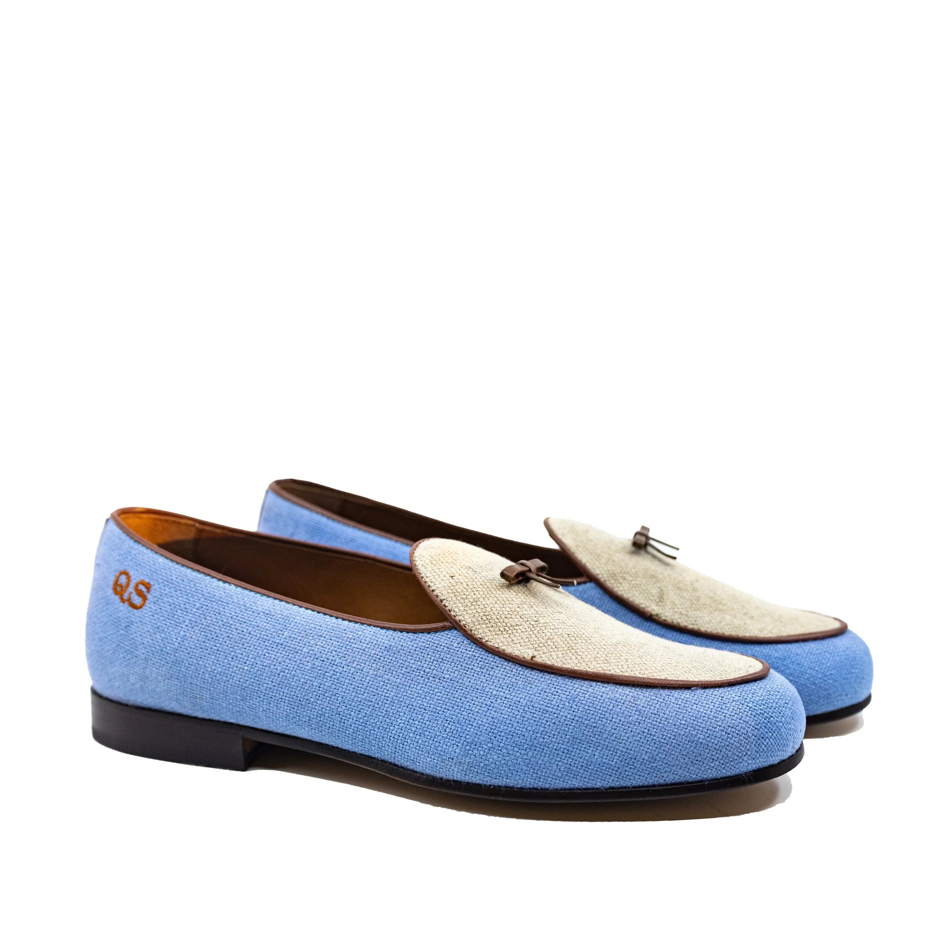 Light blue canvas loafers with a beige fabric toe medallion and brown leather accents.
